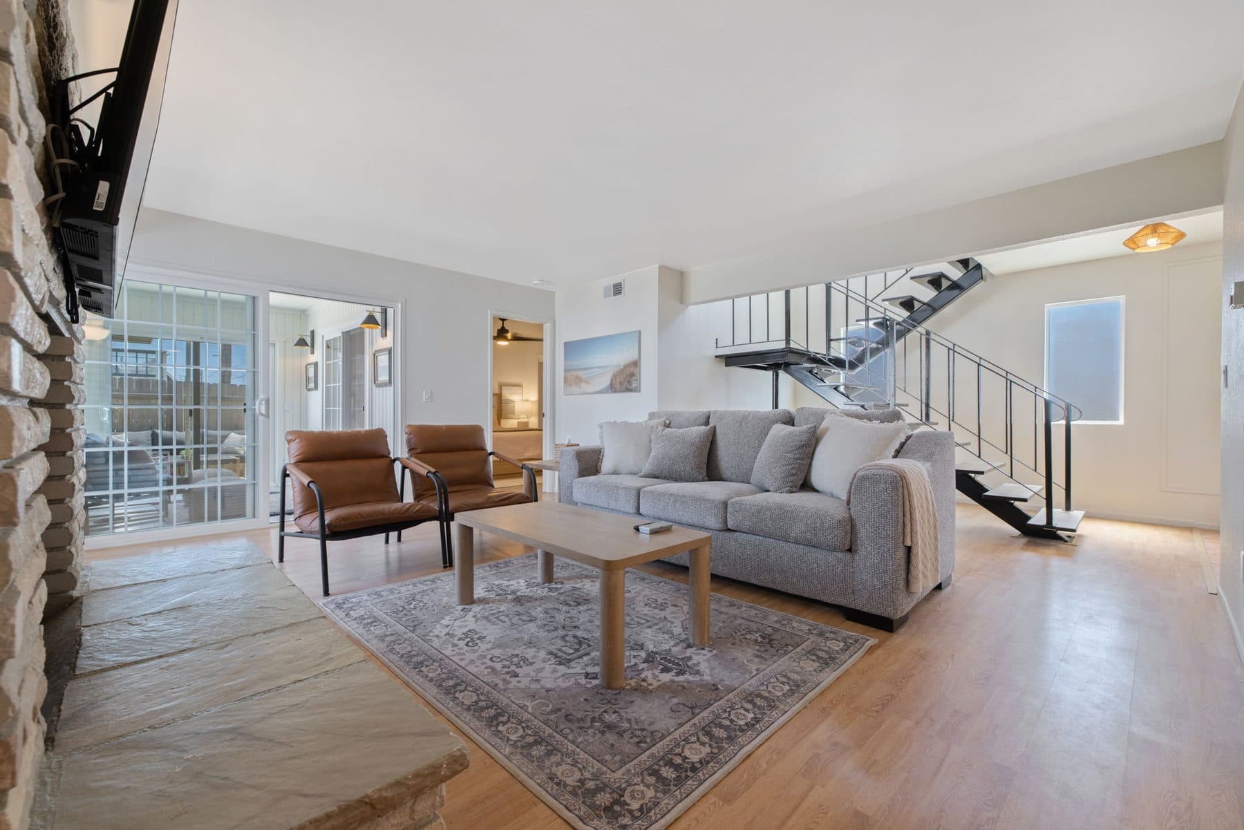 Open living room with fireplace, vaulted ceilings, and coastal light