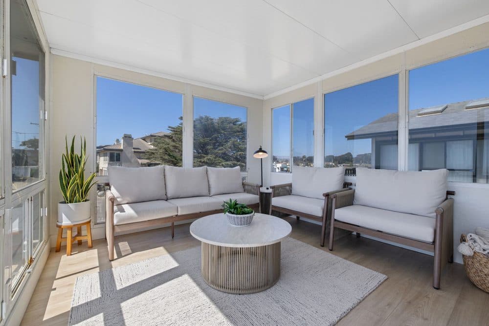Upstairs sunroom with wraparound windows, ocean views, and a chess table